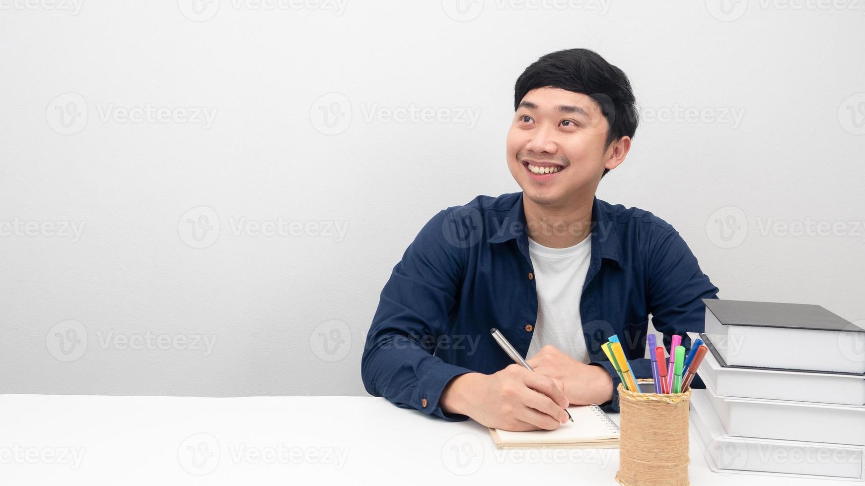 Man sit and writing pen on notebook and looking at copy space photo