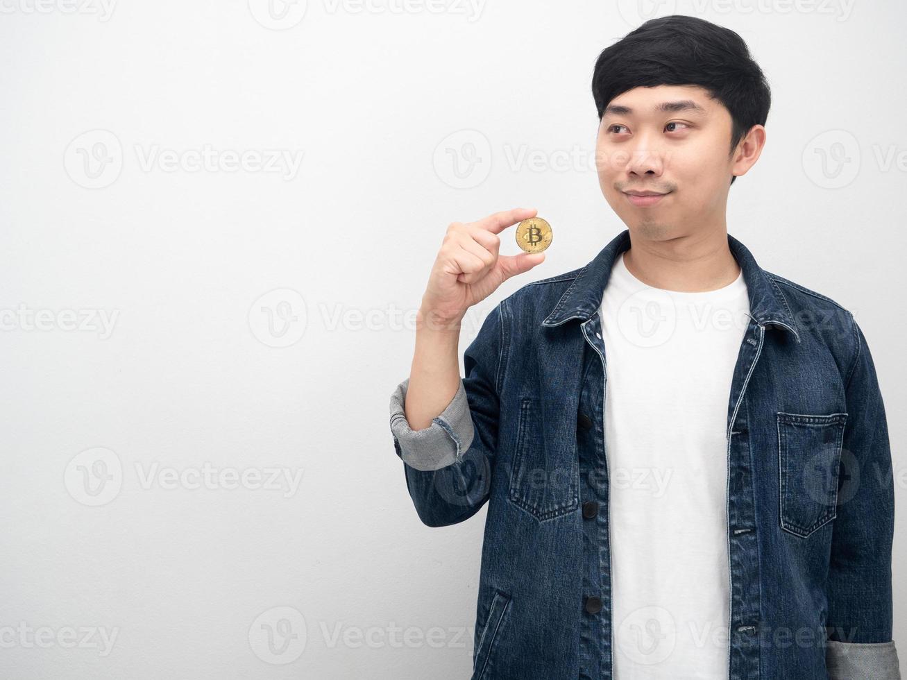 camisa de jeans de hombre asiático sosteniendo bitcoin mirando el espacio de copia foto