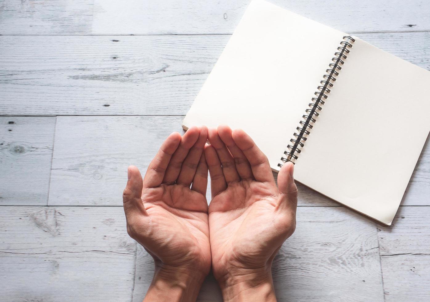 Praying hand peace concept with open book blank page on wooden white top view photo
