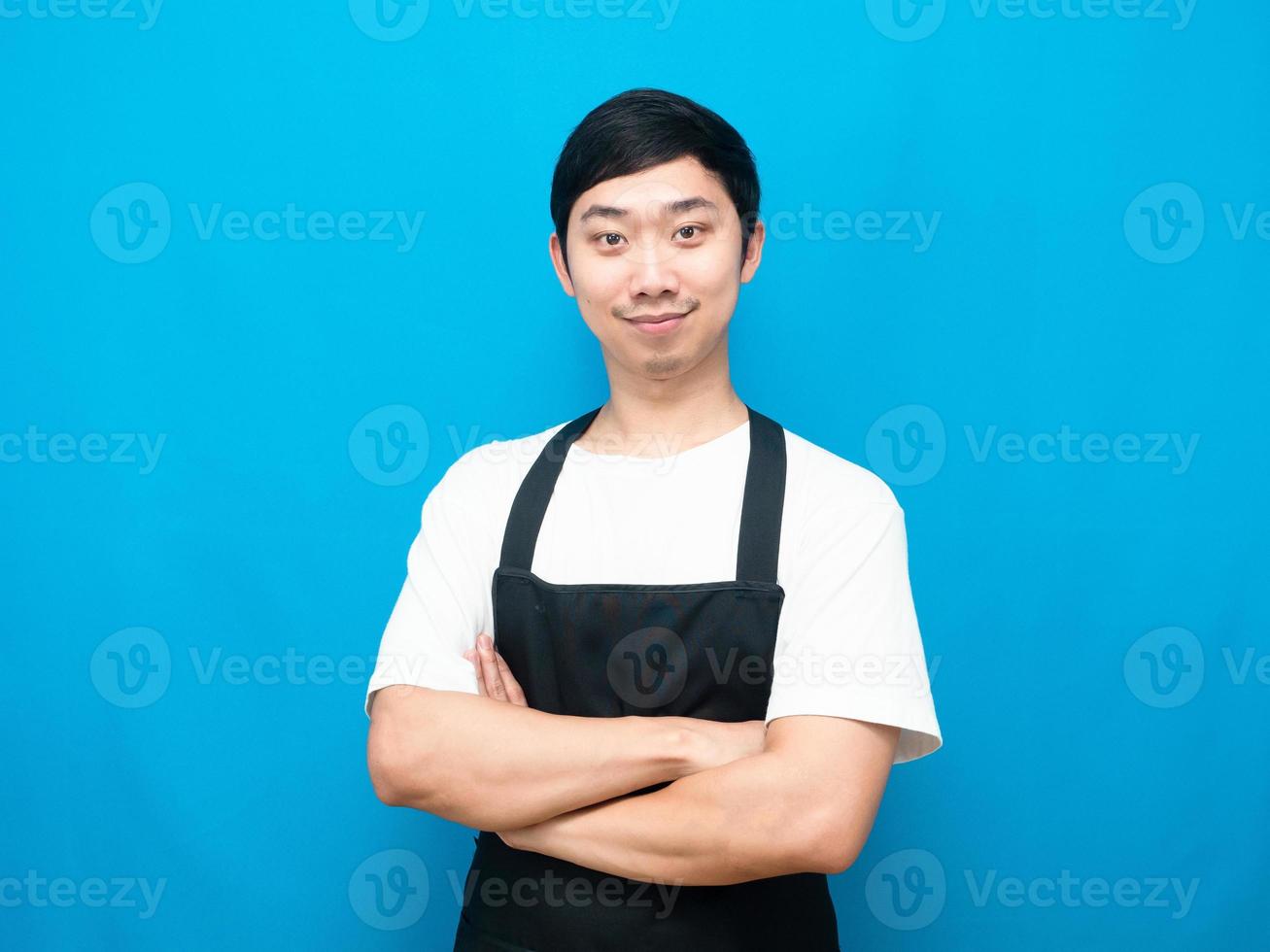 Man wearing black apron cross arm look confident blue background photo