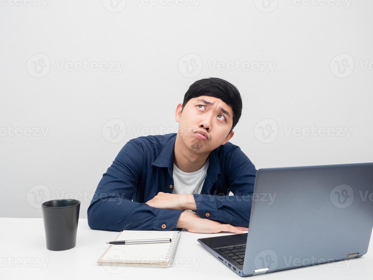 Man sit at the desk with laptop feeling bored looking up at copy space photo
