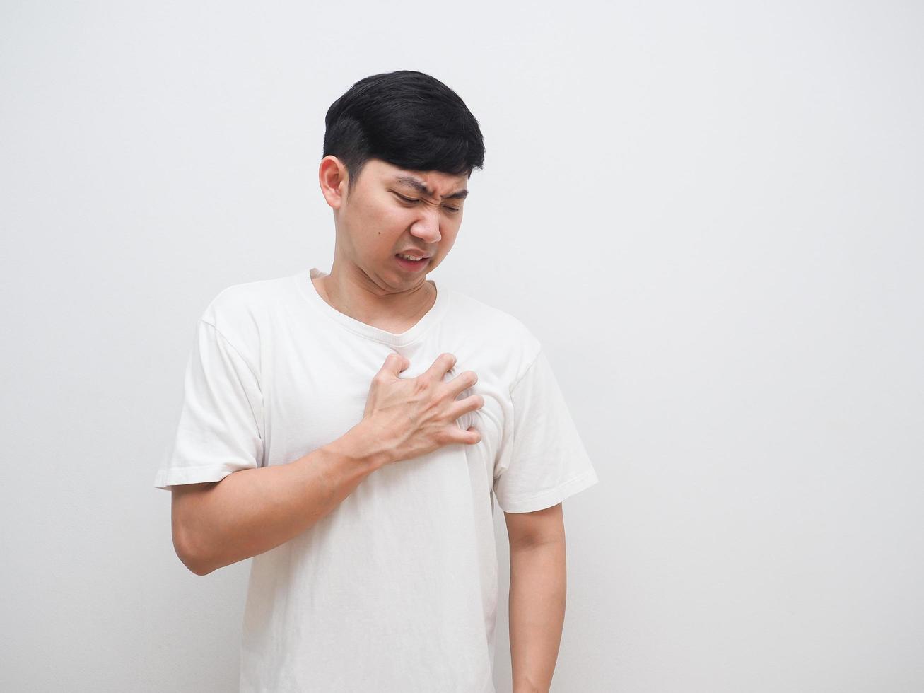 Asian man touch at his chest unhappy face on white background pain concept photo