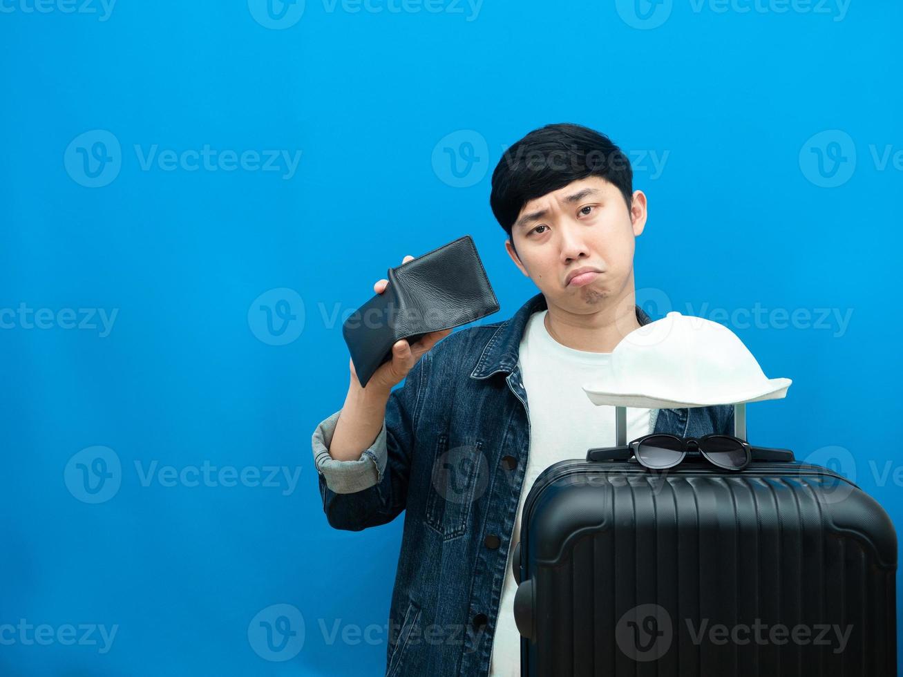 Man gesture no money with wallet feeling sad with luggage blue background photo