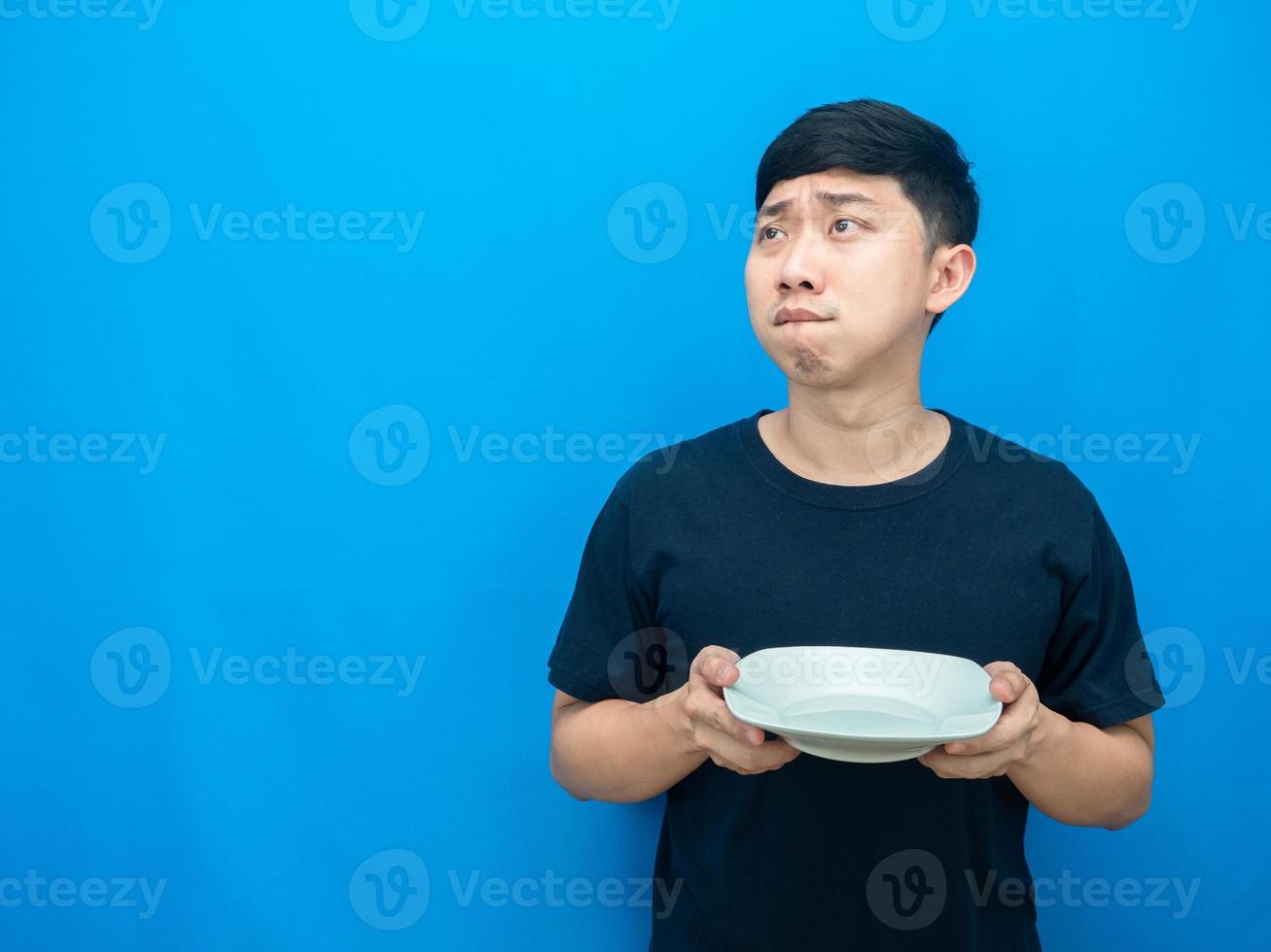 hombre gesto hambriento sosteniendo el plato y mirando el espacio de la copia pensando en la cena foto