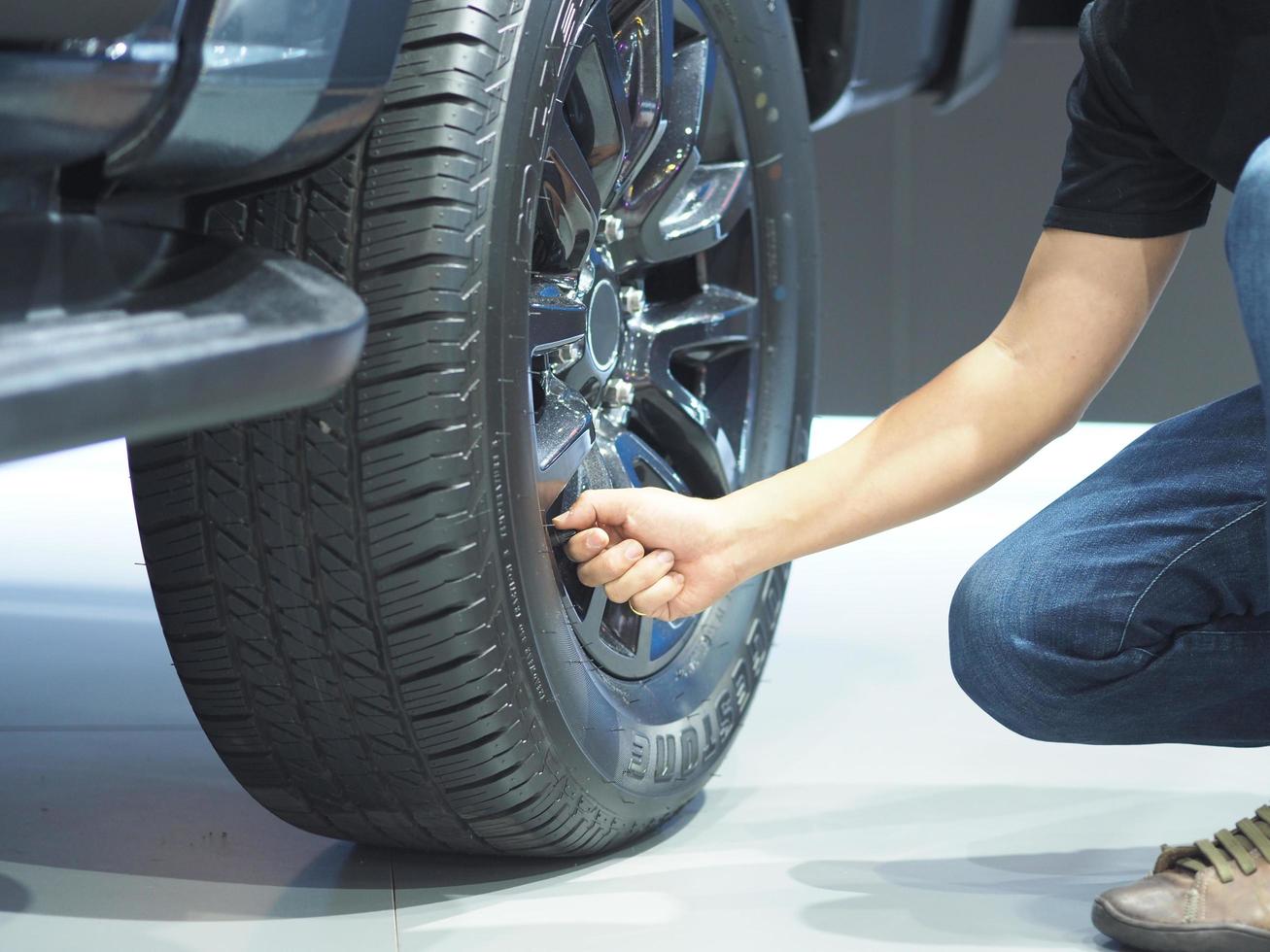 Man hand cheking big wheel of new car photo