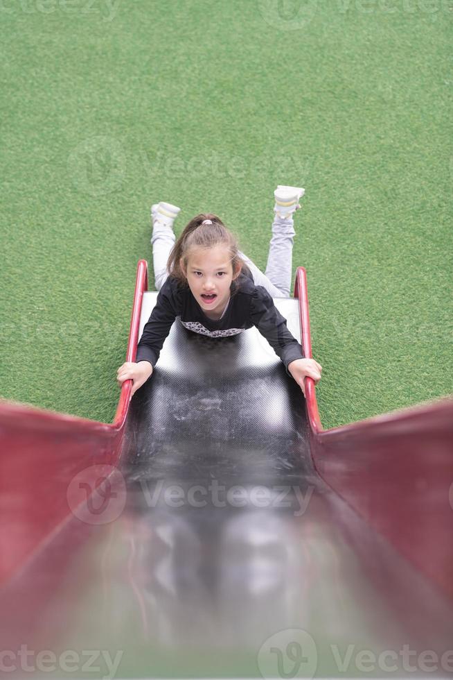 cri du chat, niña autista se desliza en un parque infantil en un parque público. foto