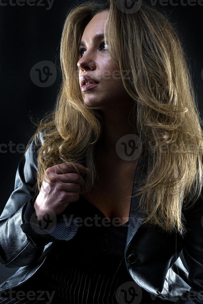 beautiful American woman posing on black background wearing black leather jacket. Fashion model wearing leather pants and jacket Fashion model wearing leather Jacket photo