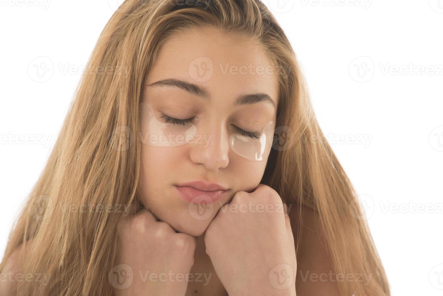 Close up of caucasian girl with natural no makeup look and white smile, take off silicone under eye patches and smiling happy, using skincare products from dark circles photo