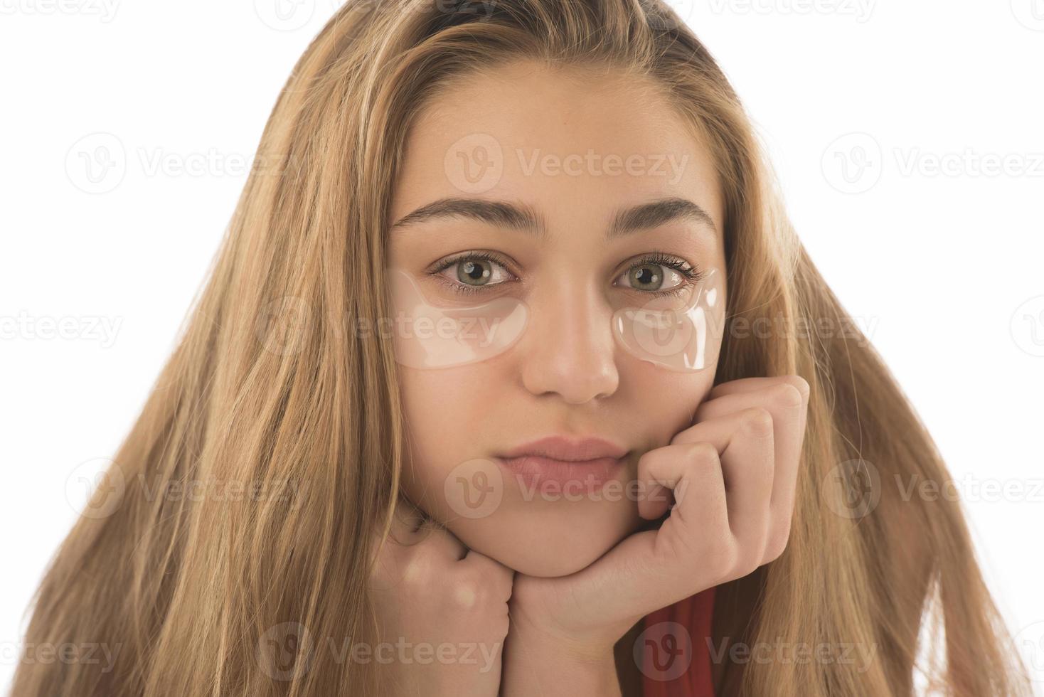 Close up of caucasian girl with natural no makeup look and white smile, take off silicone under eye patches and smiling happy, using skincare products from dark circles photo