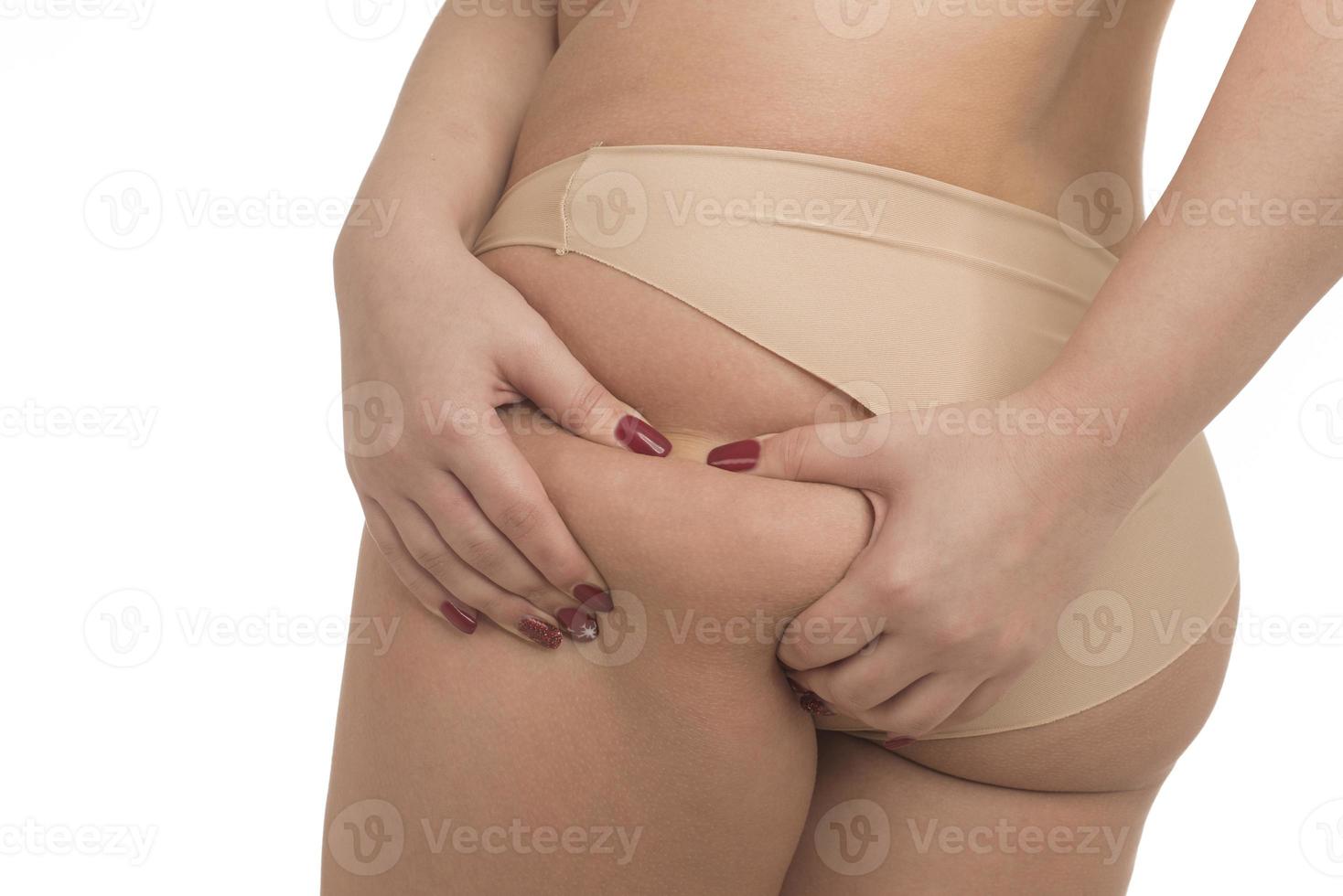 Cropped shot of a young woman grabbing skin on her thigh with excess fat photo