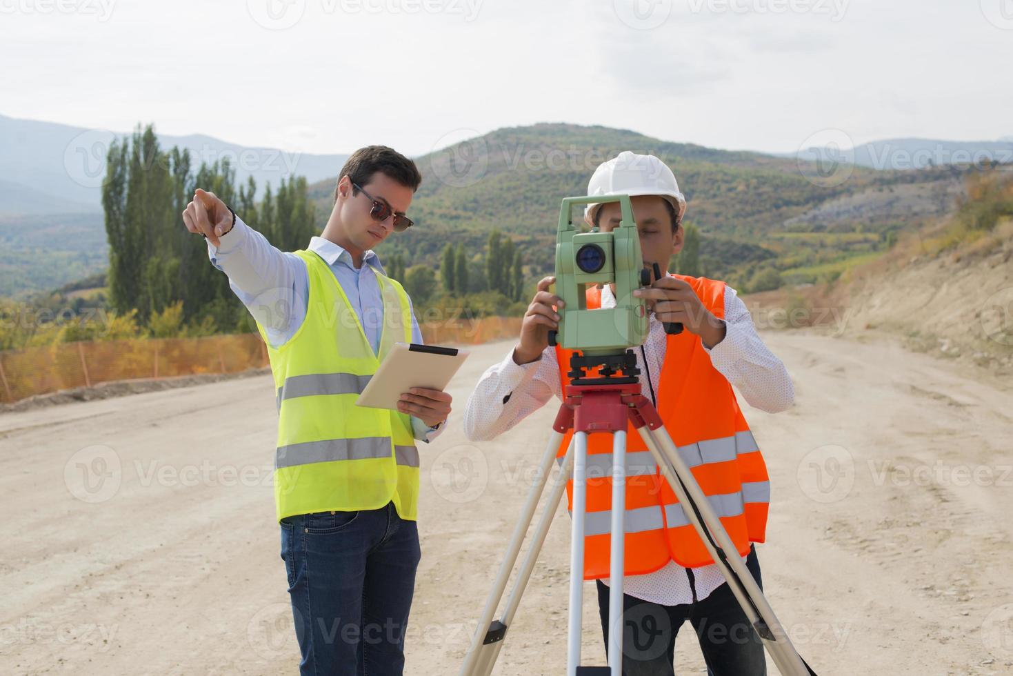 el ingeniero topógrafo está midiendo el nivel en el sitio de construcción. los topógrafos aseguran mediciones precisas antes de emprender grandes proyectos de construcción. foto