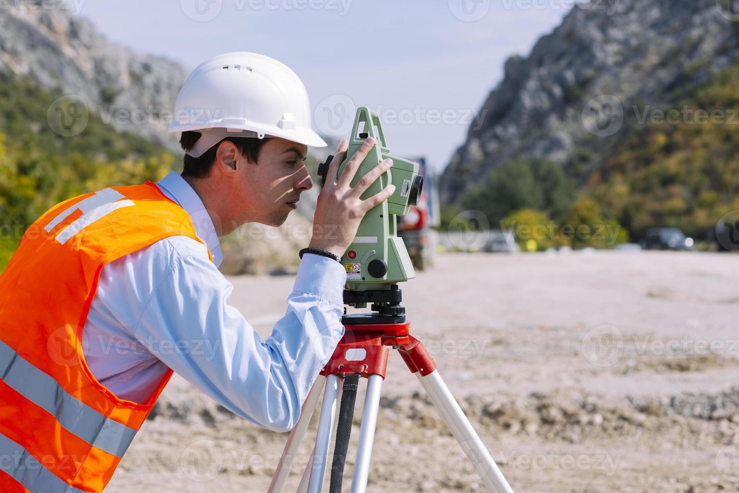 Surveyor engineer is measuring level on construction site. Surveyors ensure precise measurements before undertaking large construction projects. photo