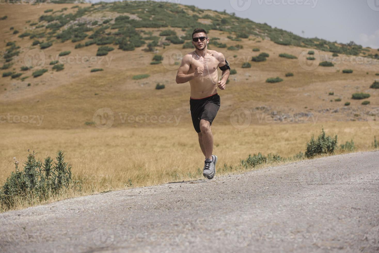 corredor joven corriendo en una carretera de montaña. entrenamiento de jogger en calzado deportivo. estilo de vida saludable y concepto deportivo. desenfoque de movimiento y enfoque selectivo. foto