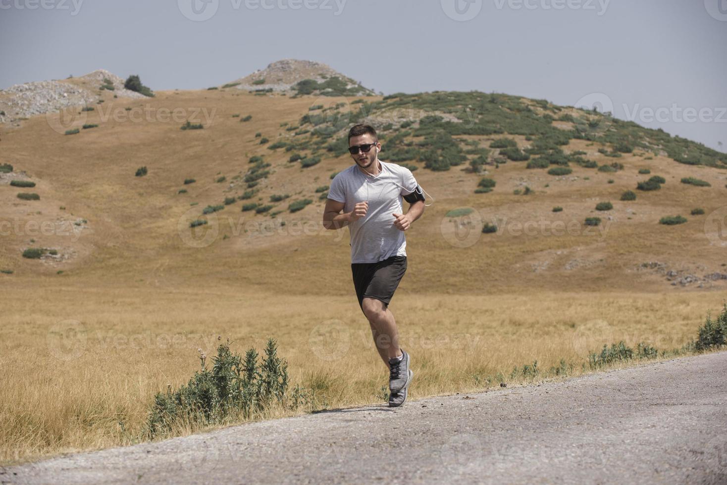 Young man runner running on a mountain road. Jogger training workout in fitness shoe. Healthy lifestyle and sport concept.  Motion blur and selective focus. photo