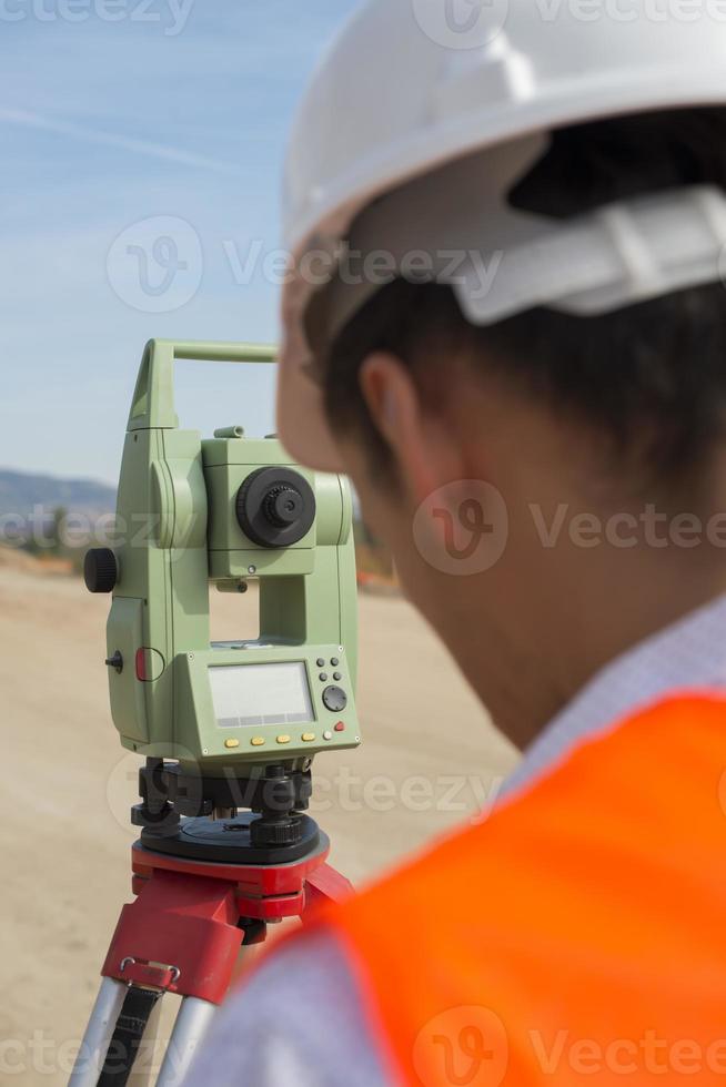 el ingeniero topógrafo está midiendo el nivel en el sitio de construcción. los topógrafos aseguran mediciones precisas antes de emprender grandes proyectos de construcción. foto