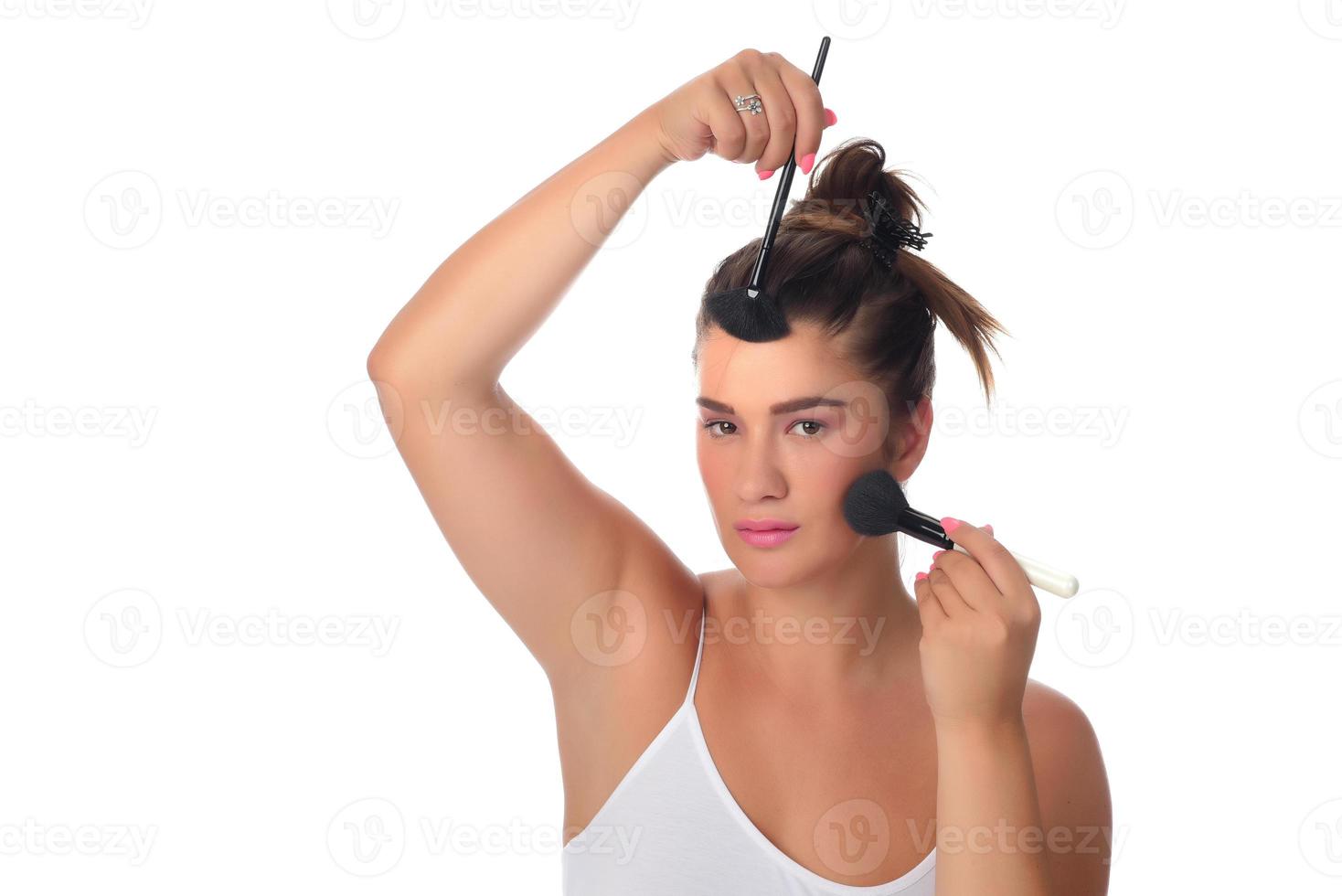 Portrait of a young woman applying make up on her face. Isolated on white background photo