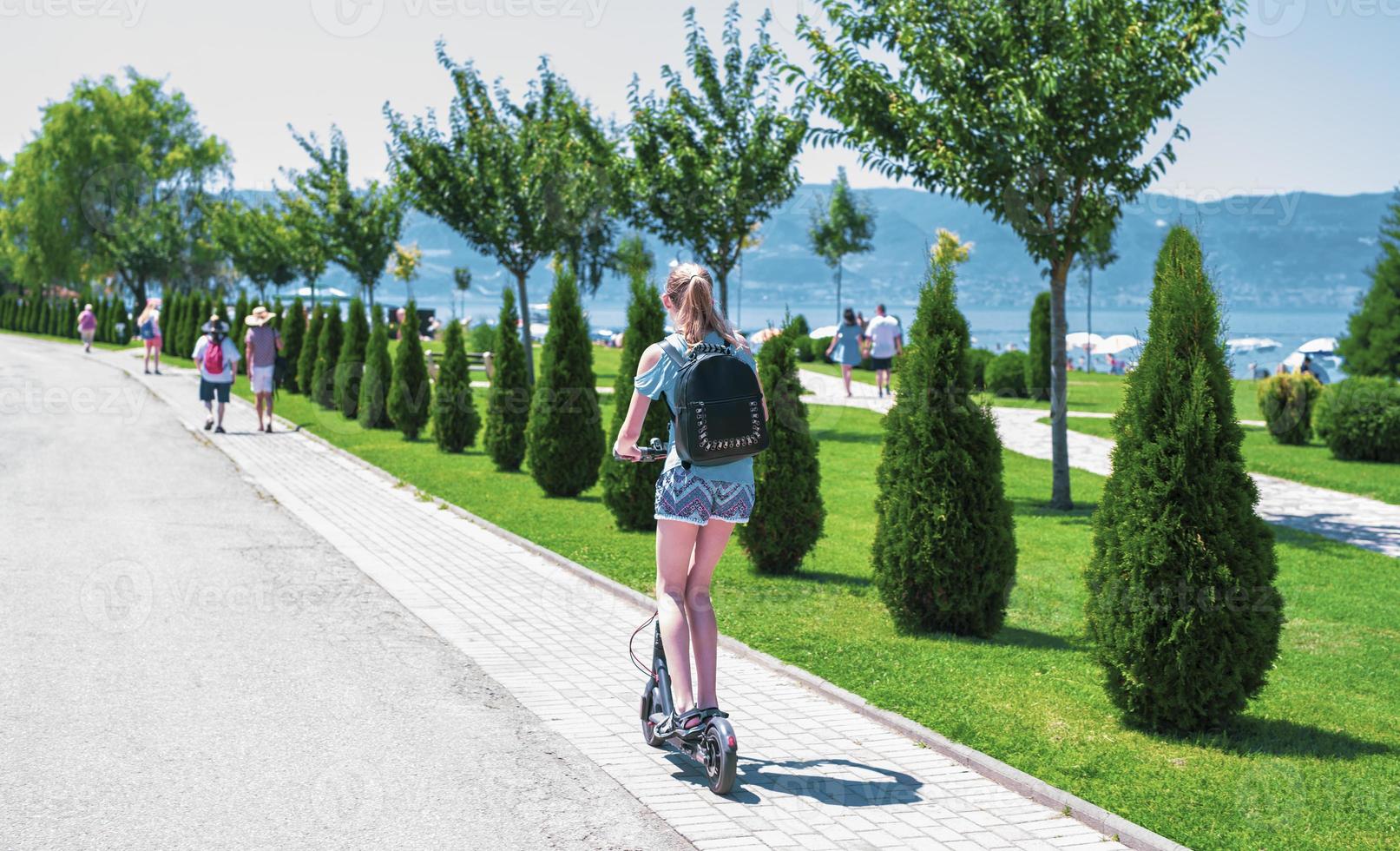 back view of a female riding electric scooter photo