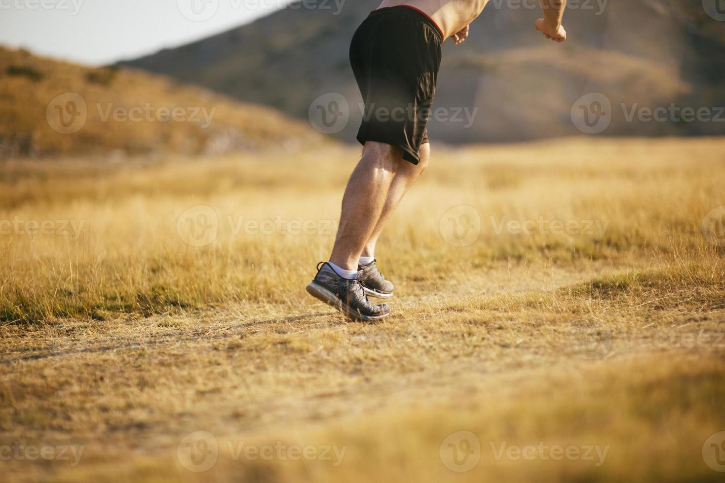 corredor joven corriendo en una carretera de montaña. entrenamiento de jogger en calzado deportivo. estilo de vida saludable y concepto deportivo. desenfoque de movimiento y enfoque selectivo. foto