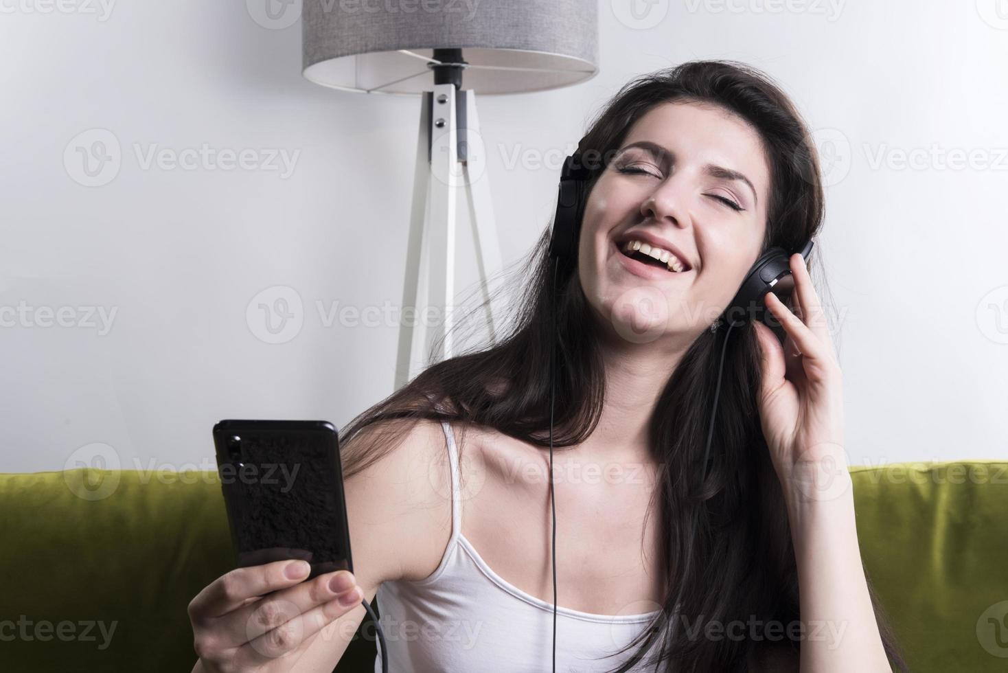 Una joven alegre escuchando música con auriculares en un apartamento tipo loft foto