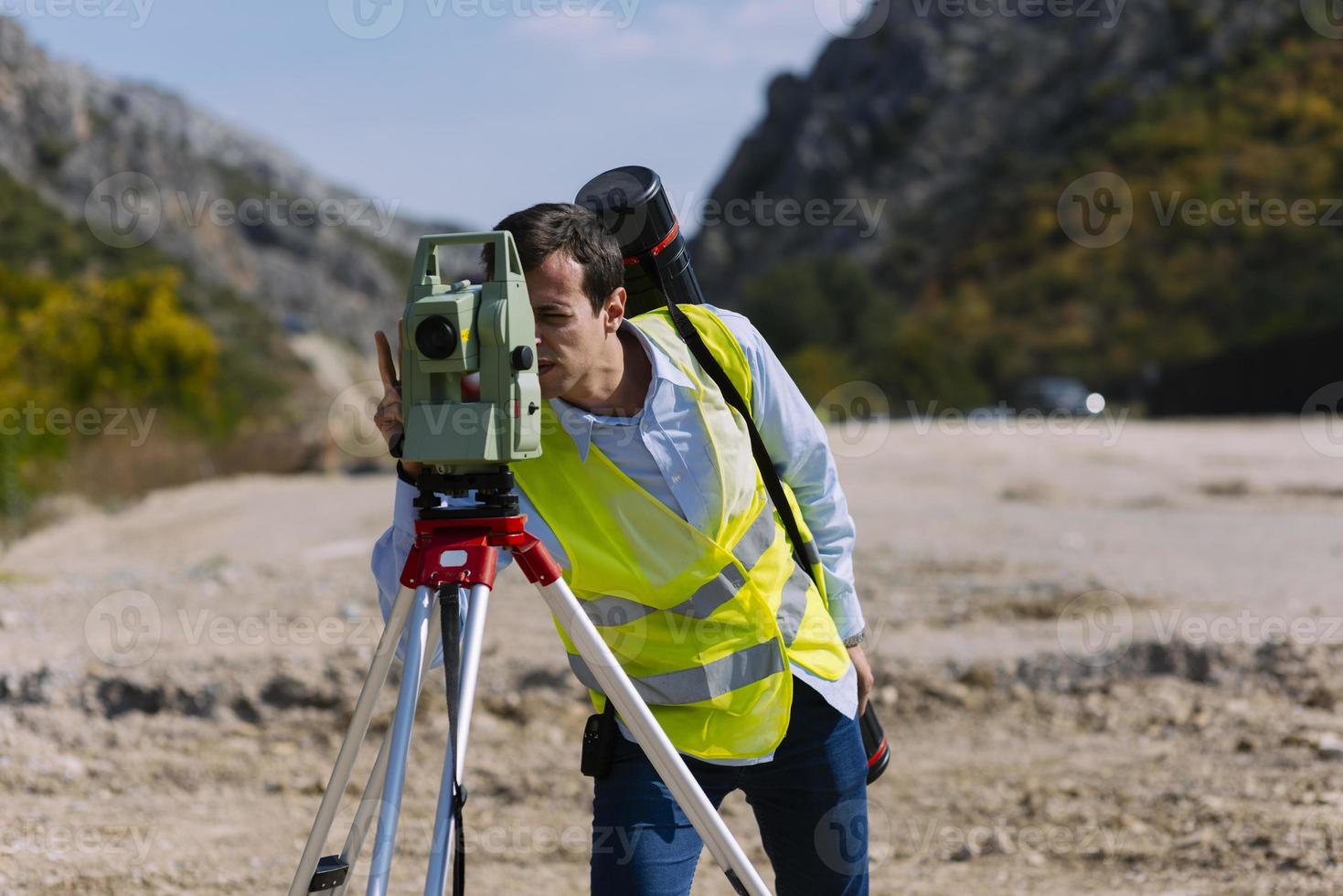 el ingeniero topógrafo está midiendo el nivel en el sitio de construcción. los topógrafos aseguran mediciones precisas antes de emprender grandes proyectos de construcción. foto