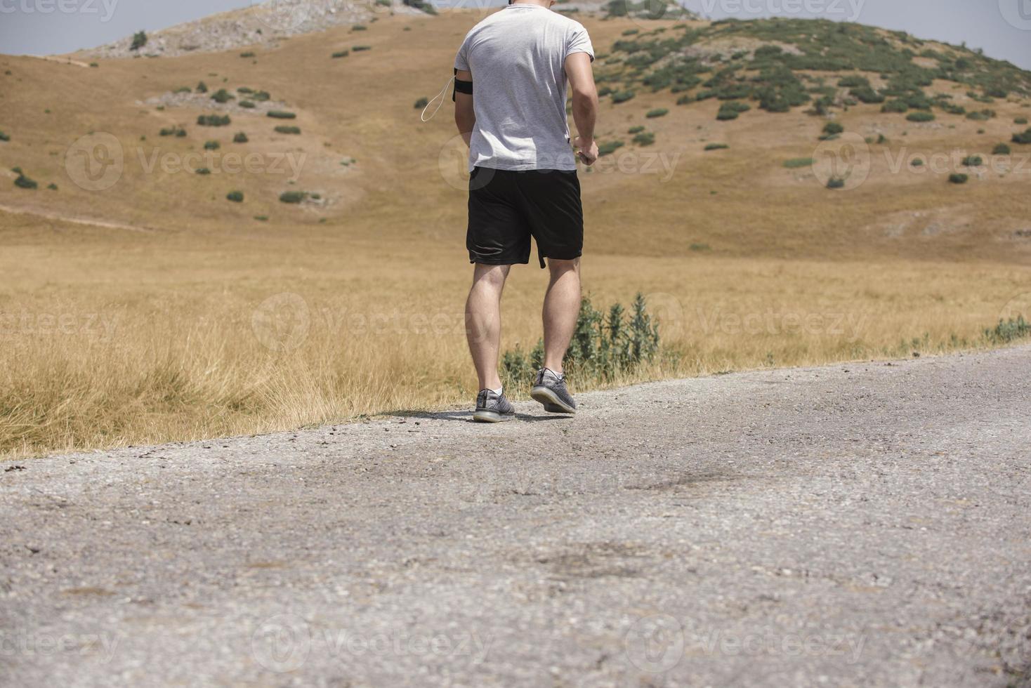 Young man runner running on a mountain road. Jogger training workout in fitness shoe. Healthy lifestyle and sport concept.  Motion blur and selective focus. photo