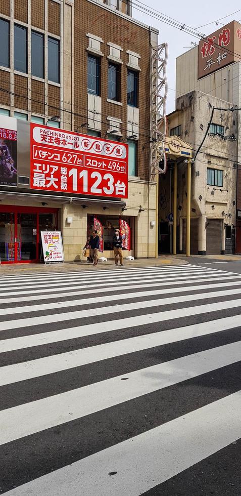 osaka, japón el 10 de abril de 2019. dos hombres asiáticos caminando por un callejón en un pueblo en osaka en la transición de primavera a verano, foto