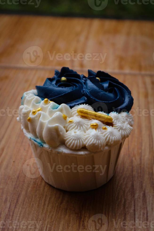 Luxurious and elegant cupcakes, with white cream and navy blue with gold sprinkles. photo