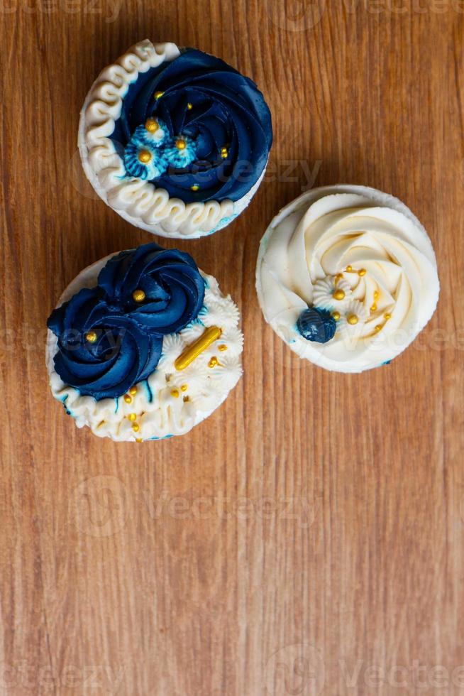 cupcakes lujosos y elegantes, con crema blanca y azul marino con chispas doradas. foto