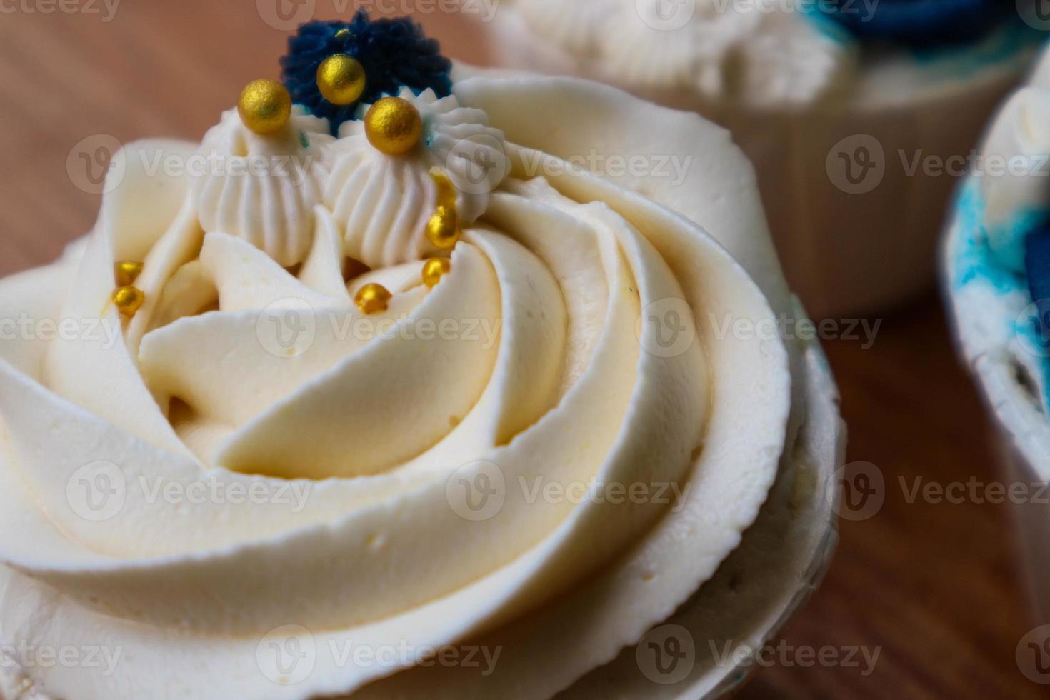 Luxurious and elegant cupcakes, with white cream and navy blue with gold sprinkles. photo