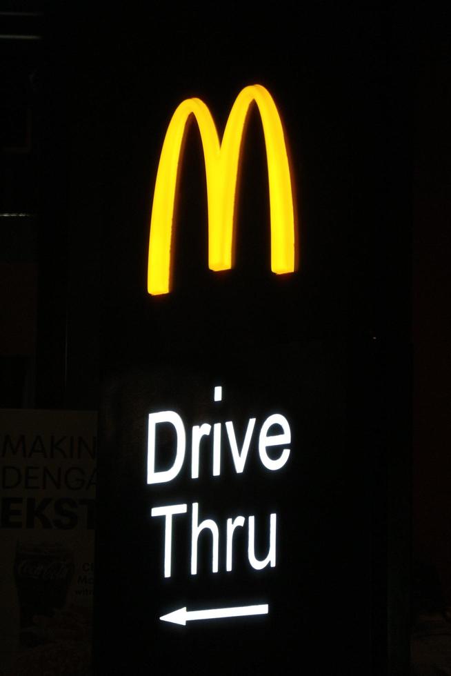 West Java, Indonesia on July 2022. Glowing McDonalds restaurant sign against night sky. Logo of Mcd Drive Thru. photo