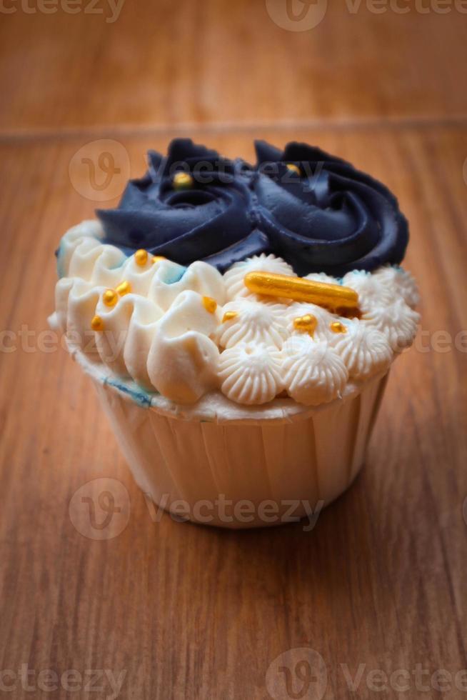 cupcakes lujosos y elegantes, con crema blanca y azul marino con chispas doradas. foto