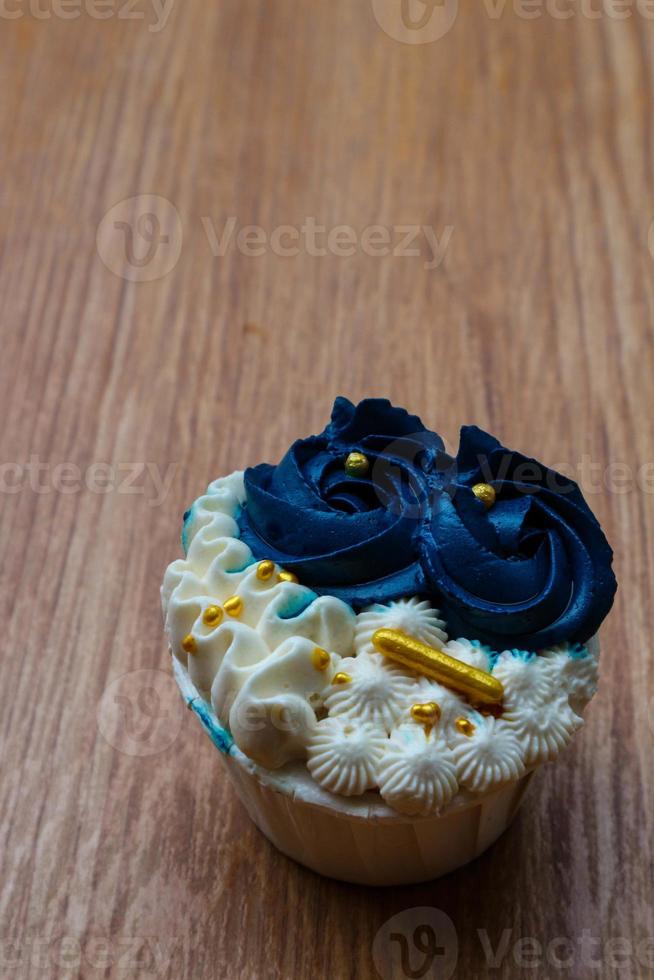 Luxurious and elegant cupcakes, with white cream and navy blue with gold sprinkles. photo