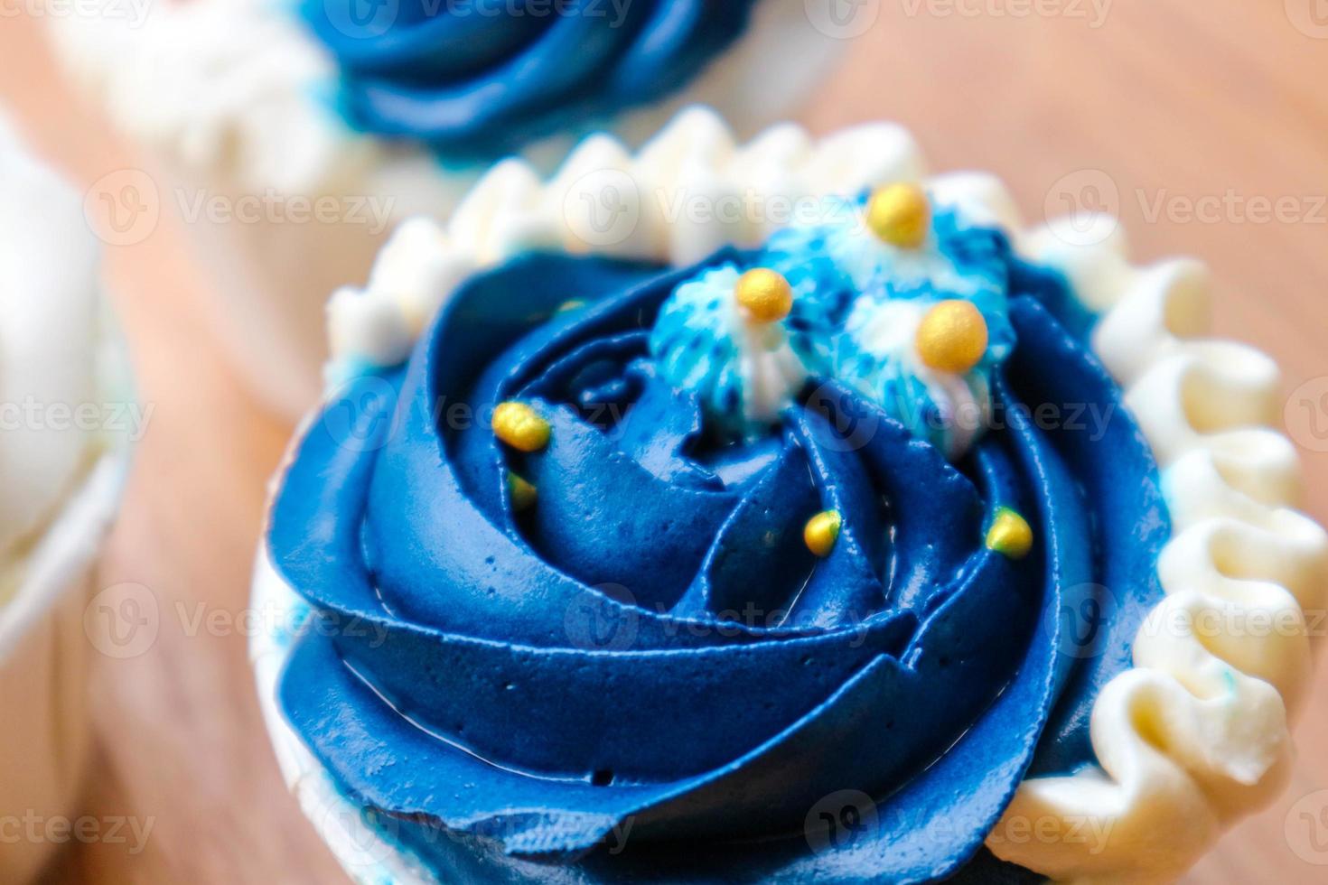 Luxurious and elegant cupcakes, with white cream and navy blue with gold sprinkles. photo