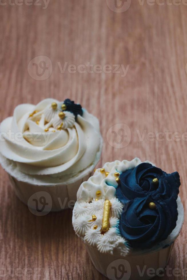 Luxurious and elegant cupcakes, with white cream and navy blue with gold sprinkles. photo