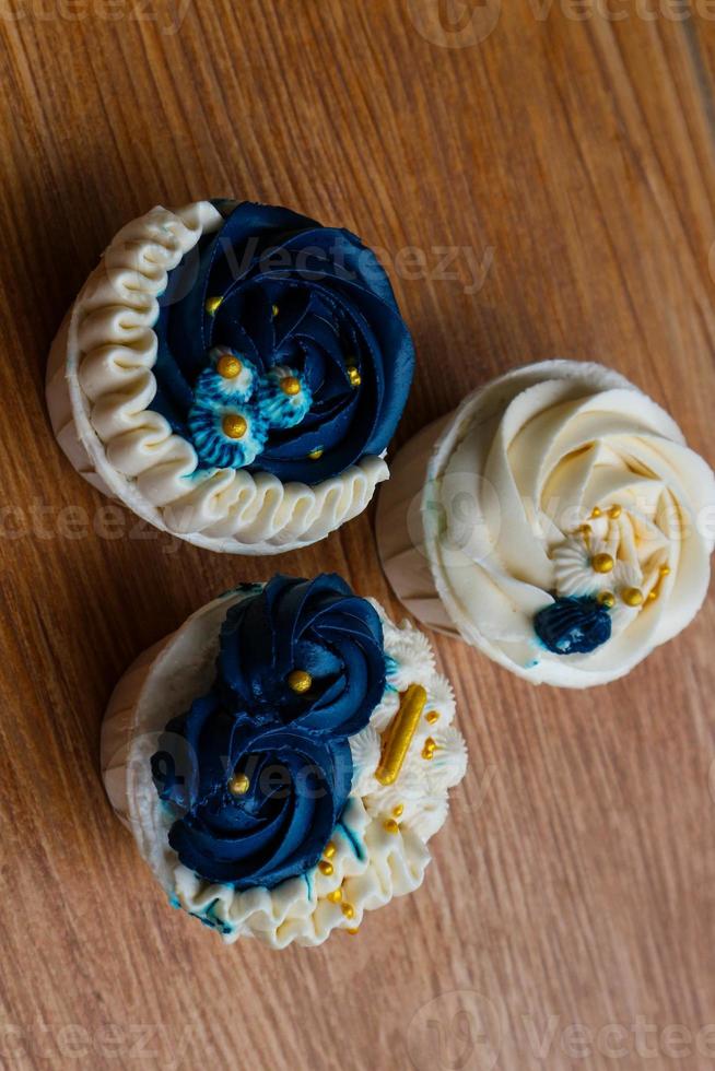 Luxurious and elegant cupcakes, with white cream and navy blue with gold sprinkles. photo