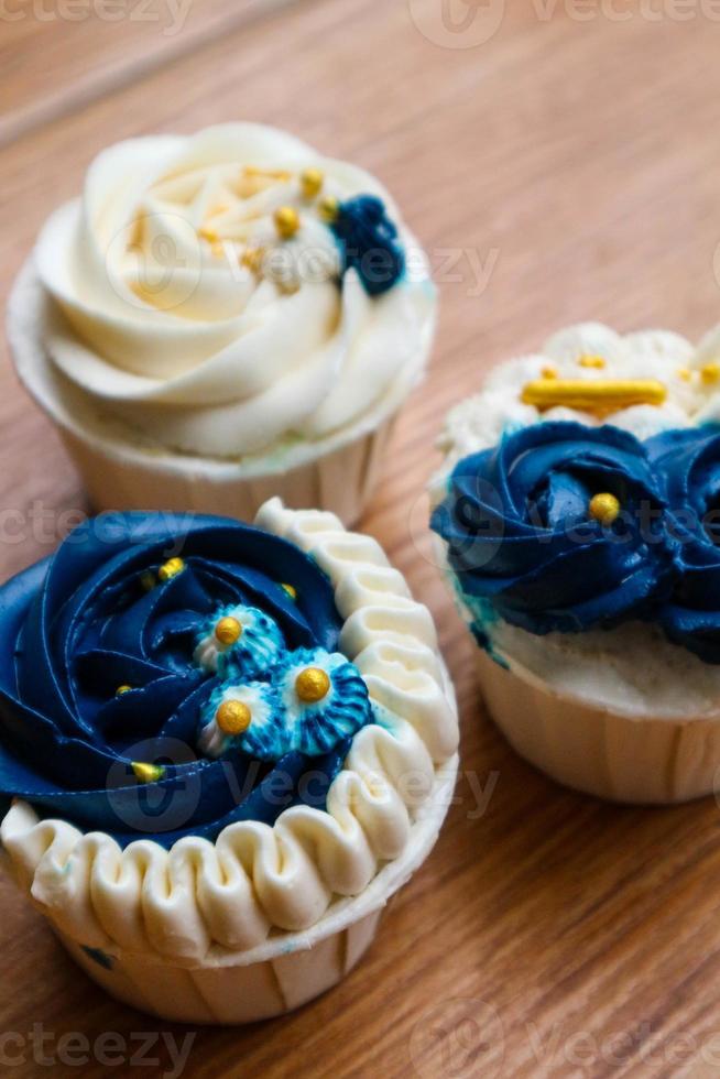 Luxurious and elegant cupcakes, with white cream and navy blue with gold sprinkles. photo