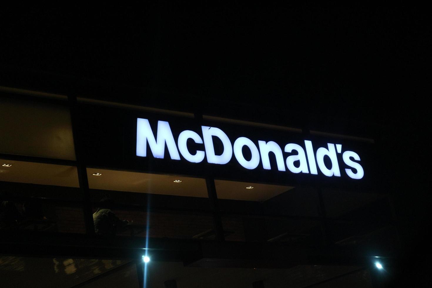 West Java, Indonesia on July 2022. Glowing McDonalds restaurant sign against night sky. Logo of Mcd Drive Thru. photo