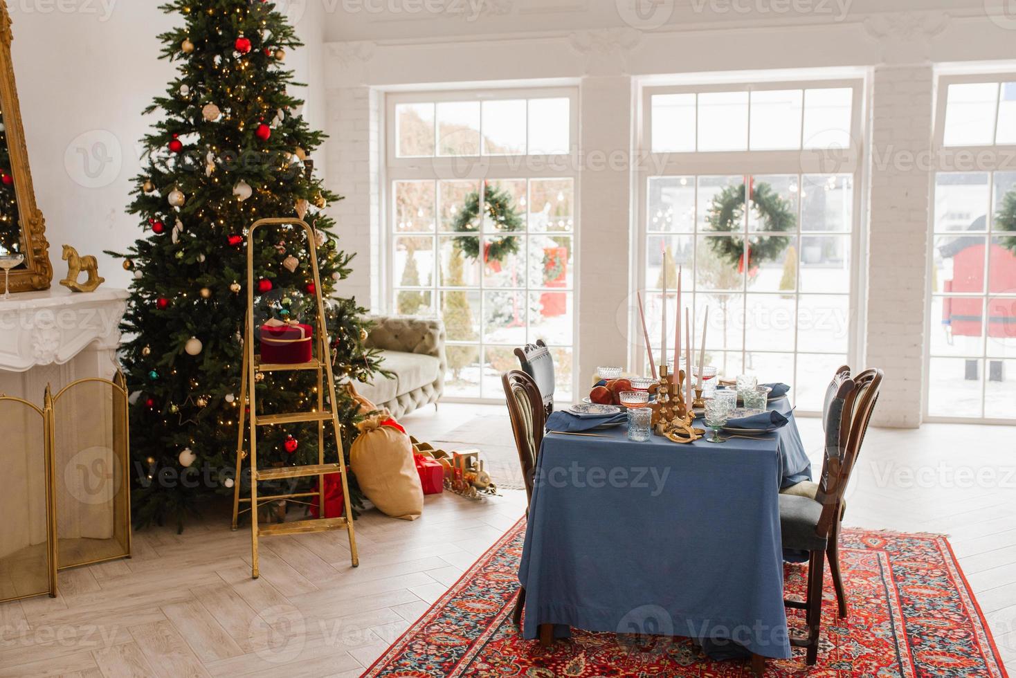 Christmas decor in the living room with large windows, dining table and Christmas tree photo