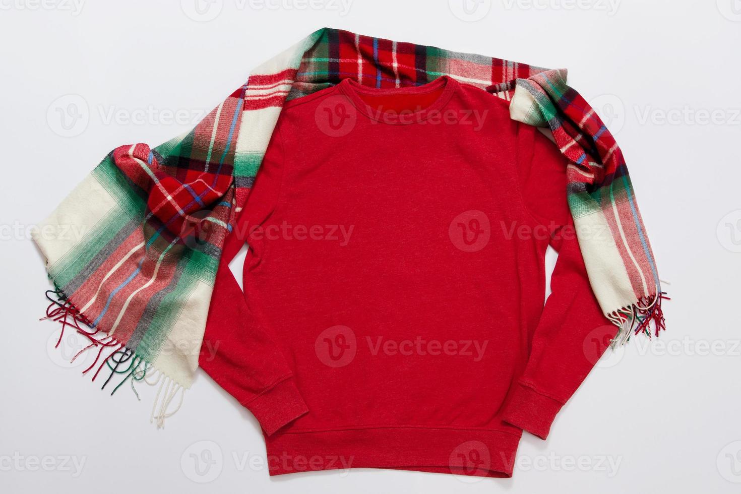 Close up red blank template sweatshirt with copy space and Christmas Holiday concept. Top view mockup hoodie and red holidays decorations on white background. Happy New Year accessories. Xmas outfit photo