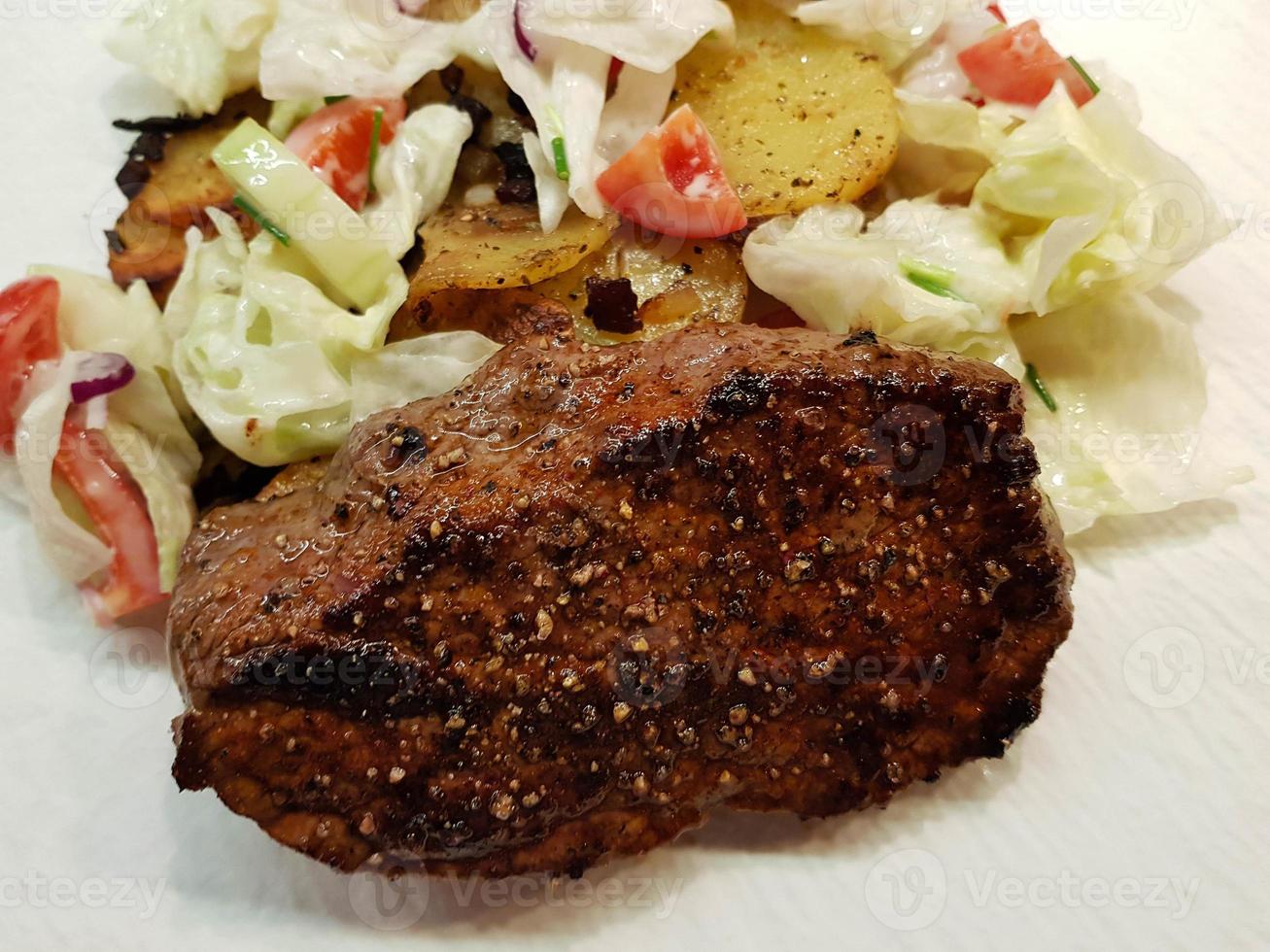 a freshly fried beef steak from the frying pan with delicious ingredients photo