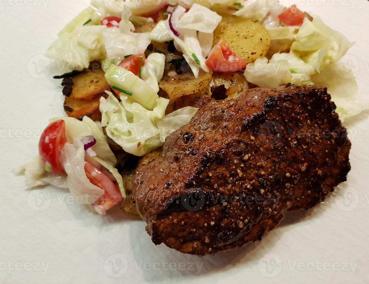 a freshly fried beef steak from the frying pan with delicious ingredients photo