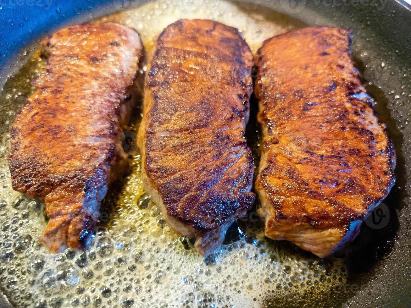 a freshly fried beef steak from the frying pan with delicious ingredients photo
