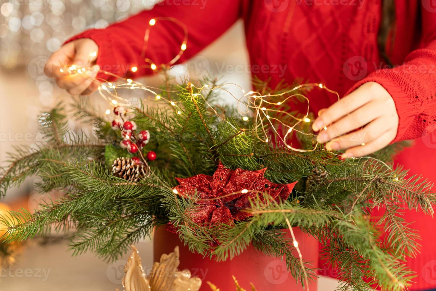 girl collects a Christmas bouquet of fir branches, flowers and Christmas tree decorations photo