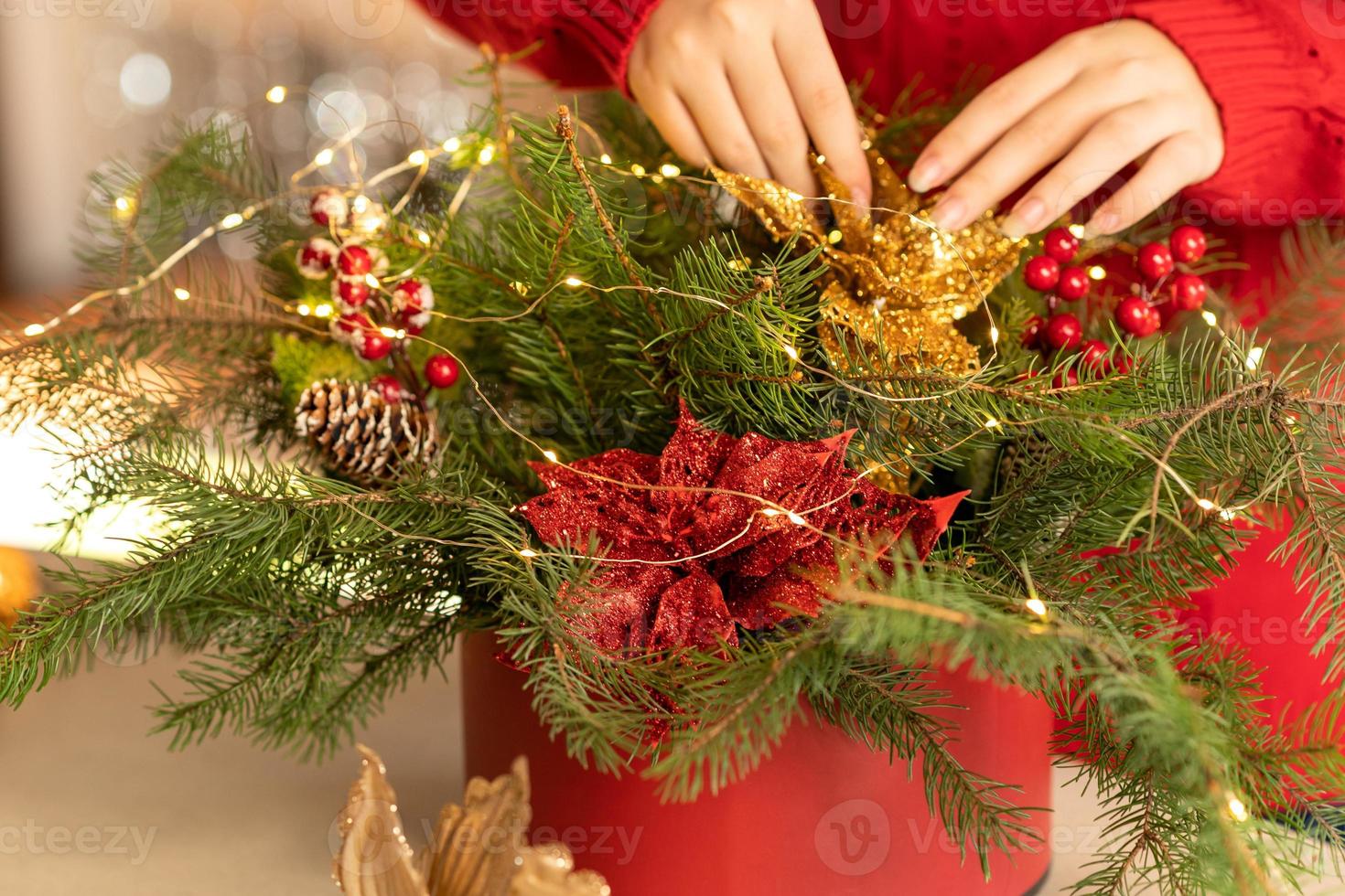 girl collects a Christmas bouquet of fir branches, flowers and Christmas tree decorations photo