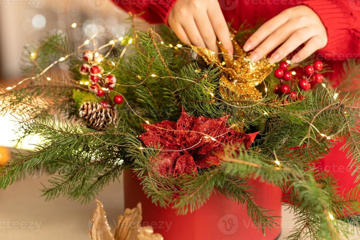 niña recoge un ramo navideño de ramas de abeto, flores y adornos de árboles de navidad foto