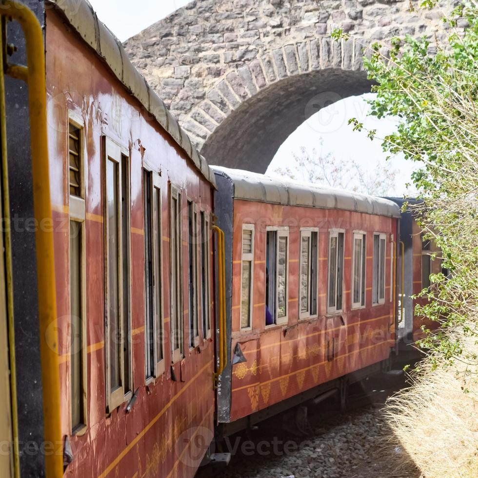 Toy Train moving on mountain slopes, beautiful view, one side mountain, one side valley moving on railway to the hill, among green natural forest. Toy train from Kalka to Shimla in India, Indian Train photo