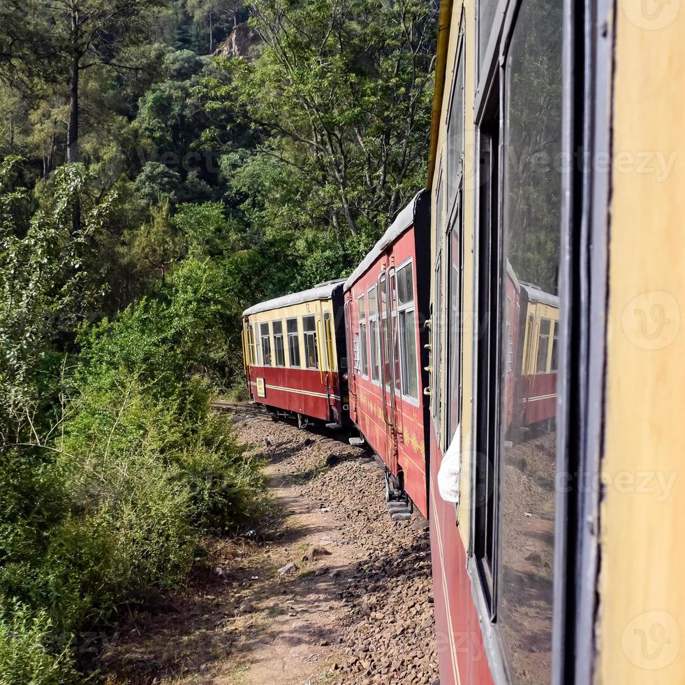 Toy Train moving on mountain slopes, beautiful view, one side mountain, one side valley moving on railway to the hill, among green natural forest. Toy train from Kalka to Shimla in India, Indian Train photo