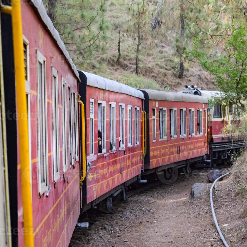 Toy Train moving on mountain slopes, beautiful view, one side mountain, one side valley moving on railway to the hill, among green natural forest. Toy train from Kalka to Shimla in India, Indian Train photo