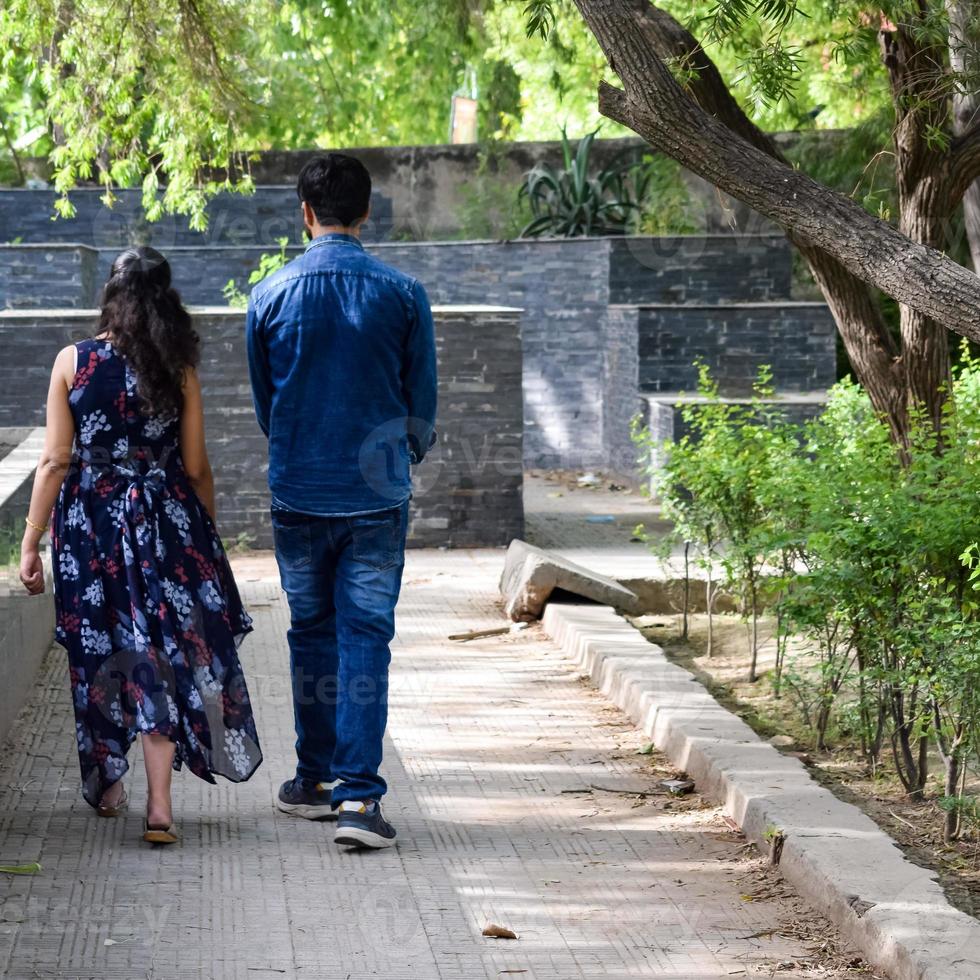 Indian couple posing for maternity baby shoot. The couple is posing in a lawn with green grass and the woman is falunting her baby bump in Lodhi Garden in New Delhi, India photo