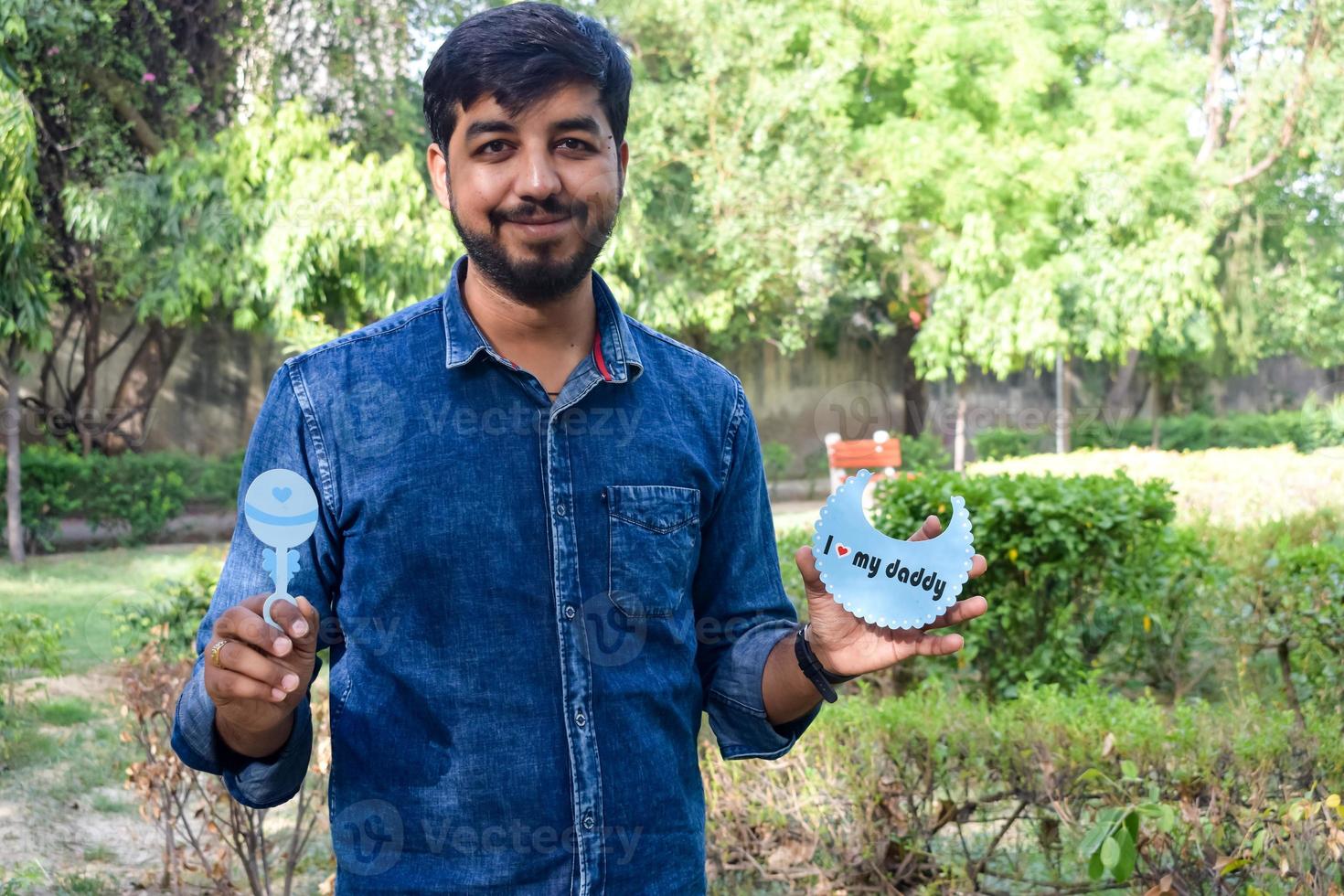 Indian couple posing for maternity baby shoot. The couple is posing in a lawn with green grass and the woman is falunting her baby bump in Lodhi Garden in New Delhi, India photo